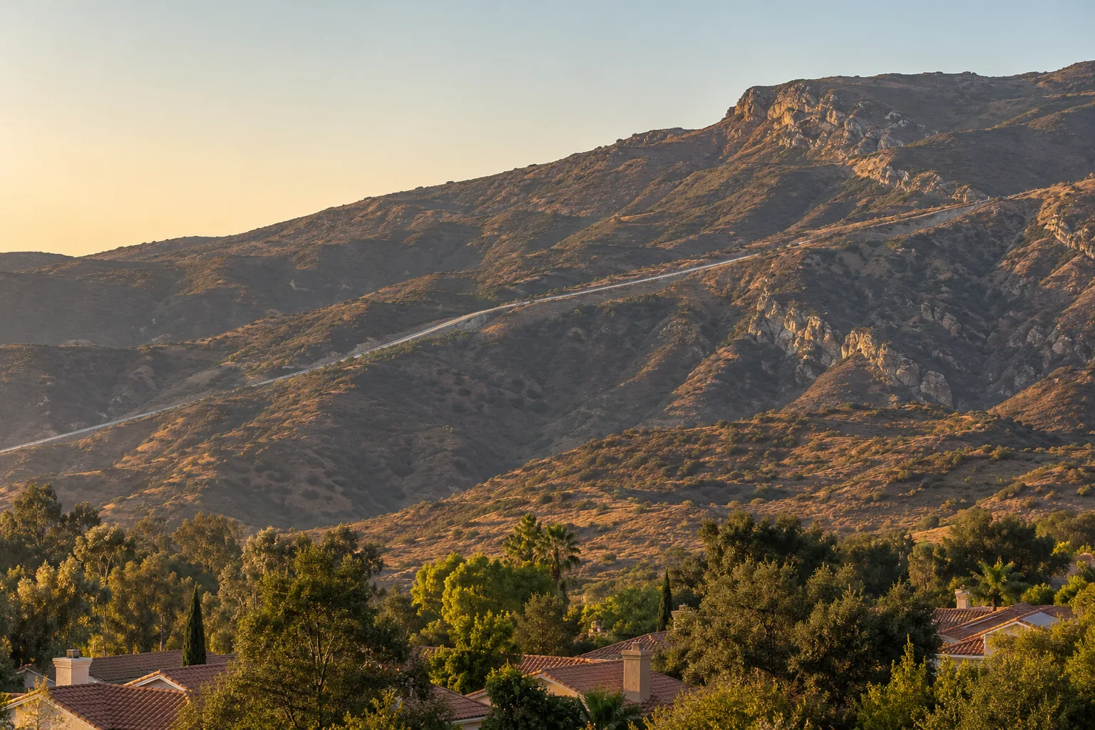 The brown chaparral escarpment of the Conejo Grade rising east of Camarillo at golden hour
