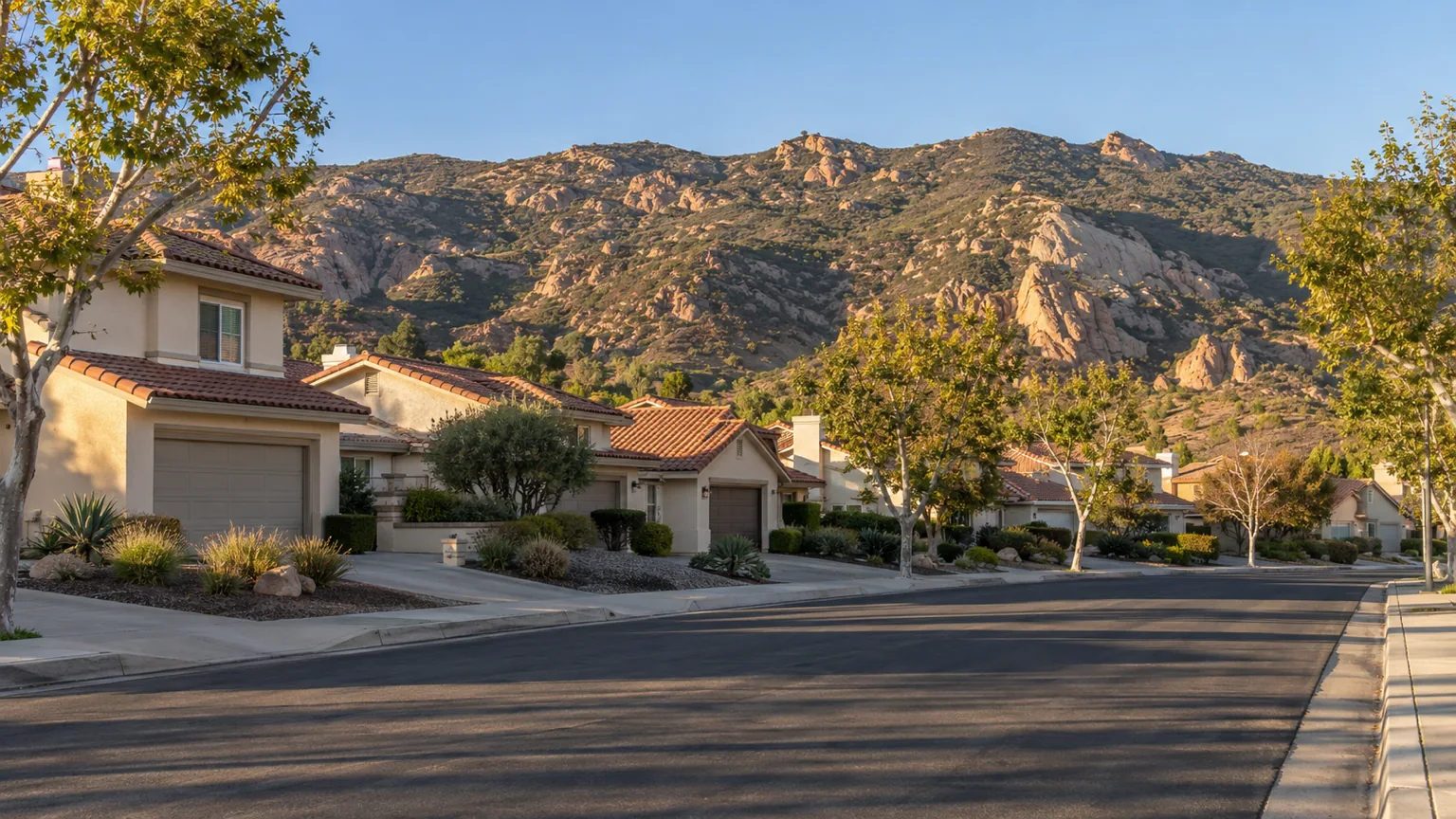 Stucco tract homes on a Simi Valley street with the tan sandstone Simi Hills rising behind
