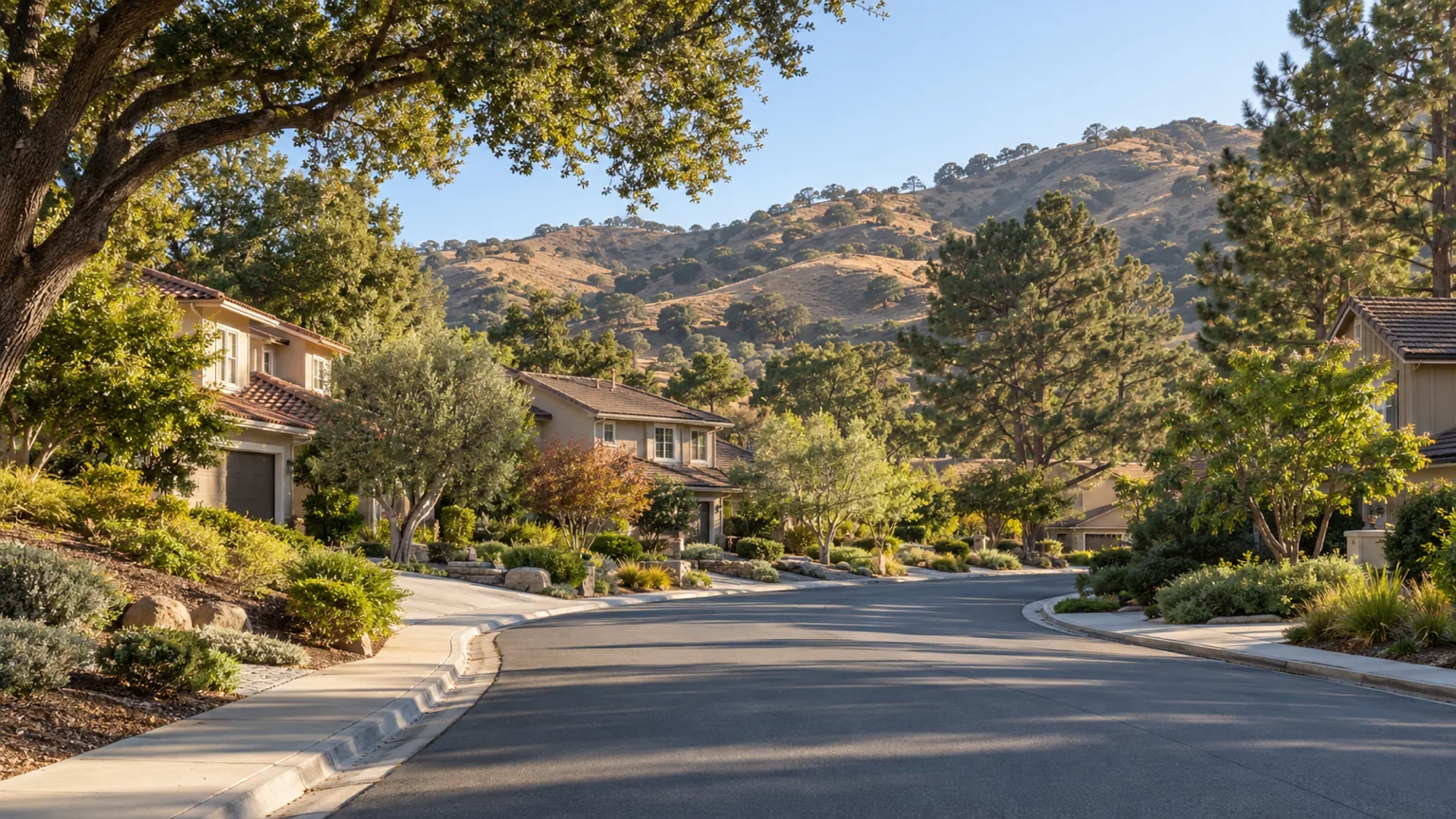 1970s two-storey homes with tile roofs and mature trees on a quiet Westlake Village street below oak hills