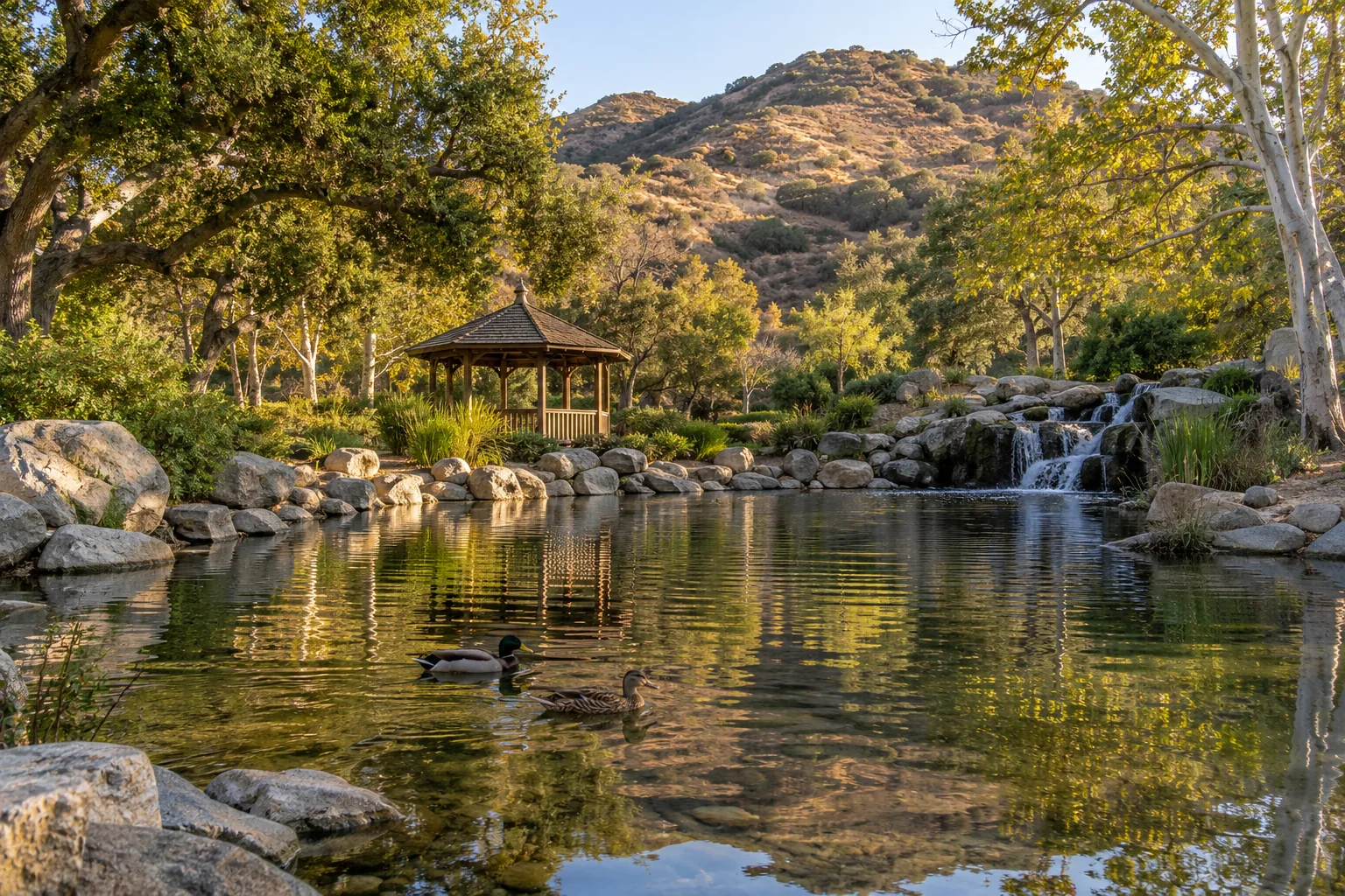 Duck pond with a small rocky waterfall and oak trees at Oak Canyon Community Park in Oak Park, CA