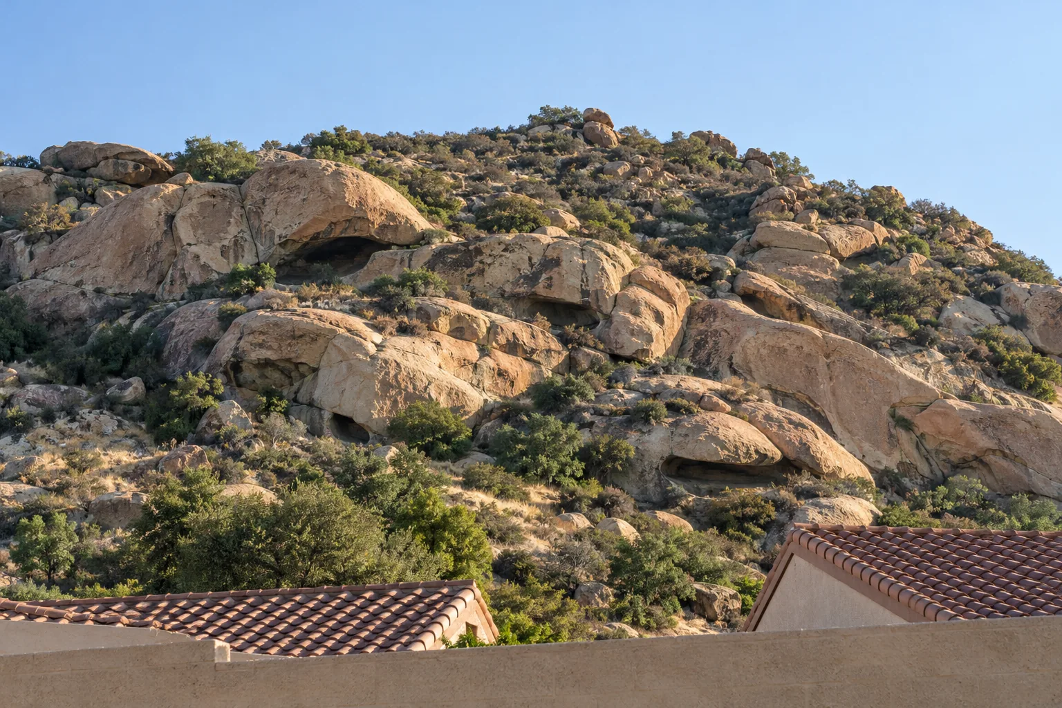 Weathered tan sandstone boulders of the Simi Hills above tile rooftops at the edge of Simi Valley
